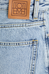 Toteme organic cotton denim skirt size 44/14, new with tags, shown on a hanger in a natural setting.