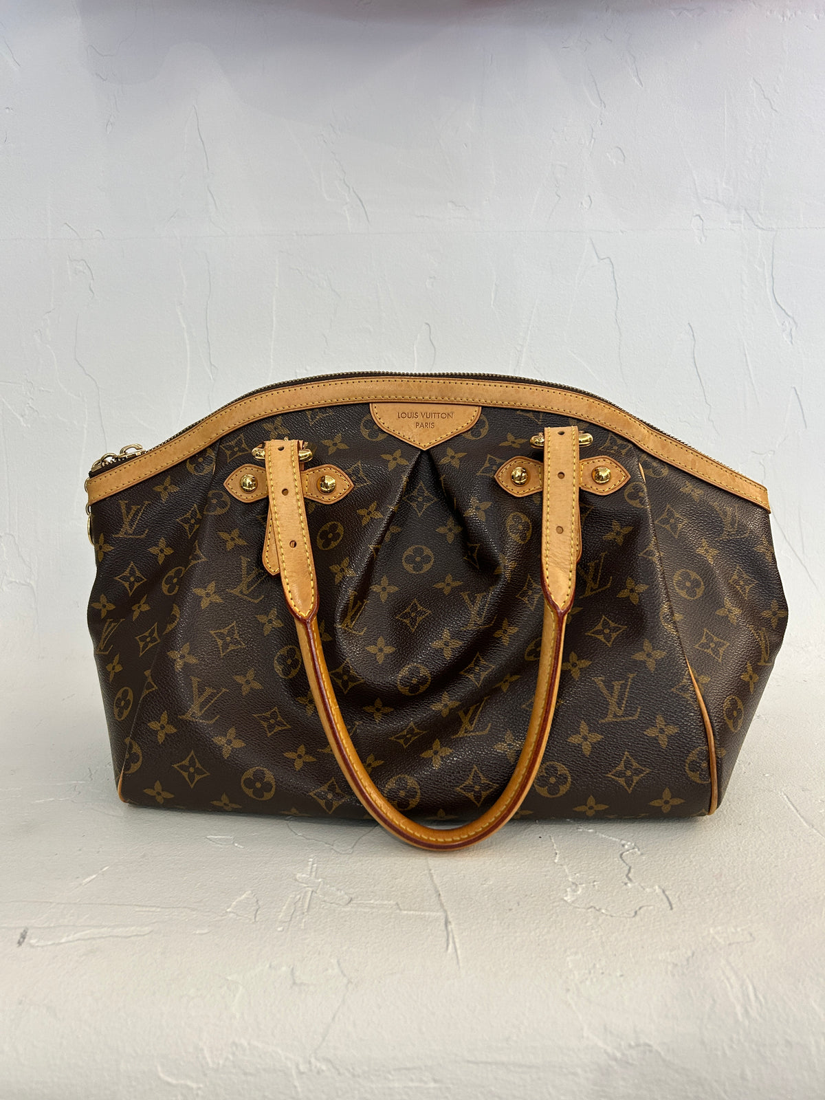 Louis Vuitton Monogram Tivoli GM bag with leather handles and gold hardware, showcasing the iconic monogram canvas.