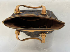 Louis Vuitton Monogram Tivoli GM bag with leather handles and gold hardware, featuring the signature LV monogram pattern.