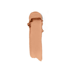Ilia Skin Rewind Blurring Foundation and Concealer Complexion Stick in various shades, displayed on a natural beech wood background.